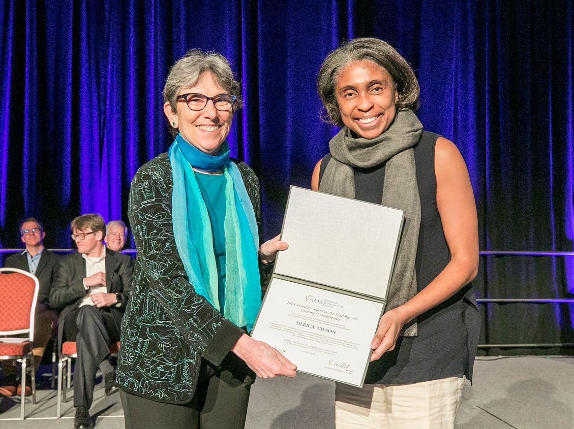 Two smiling women accepting an award certificate
